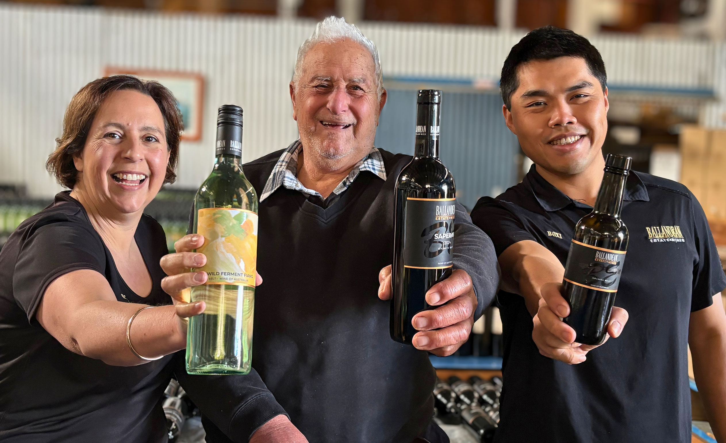 Brunette woman, older man and young man hold winning bottles of wine in front of them, smiling